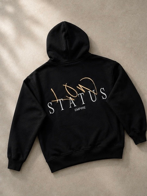 Black hoodie with 'LOW STATUS' text on a beige background